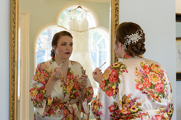 Bride getting ready with lipstick in mirror at The Waterview in Monroe, Connecticut