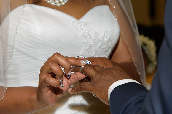 Bride putting ring on grooms finger, for African American Wedding Ceremony