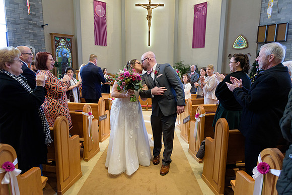 Bride and groom kiss while walking down the aisle, catholic wedding ceremony