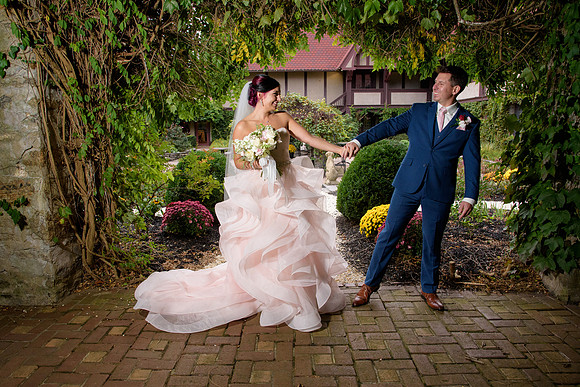 Bride in pink dress and groom in blue suit in the gardens at Saint Clements Castle in Portland Connecticut