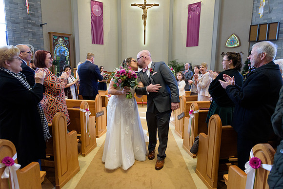 Bride and groom kiss while walking down the aisle, catholic wedding ceremony